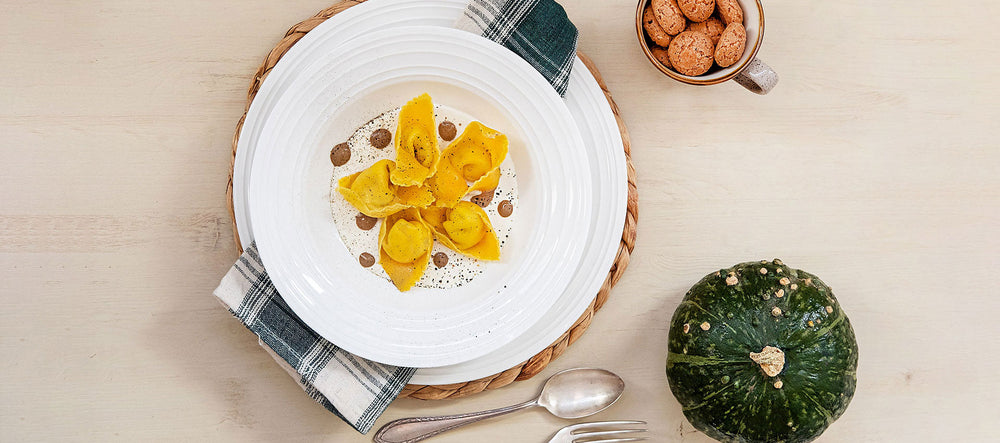 Tortelli di zucca su fonduta e crema di aglio nero